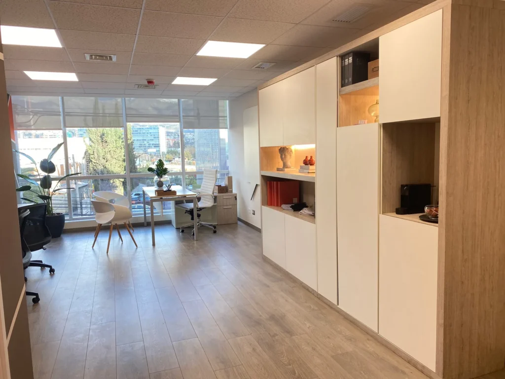 Ambiente de oficina con mesa, sillas y mobiliario de guardado.