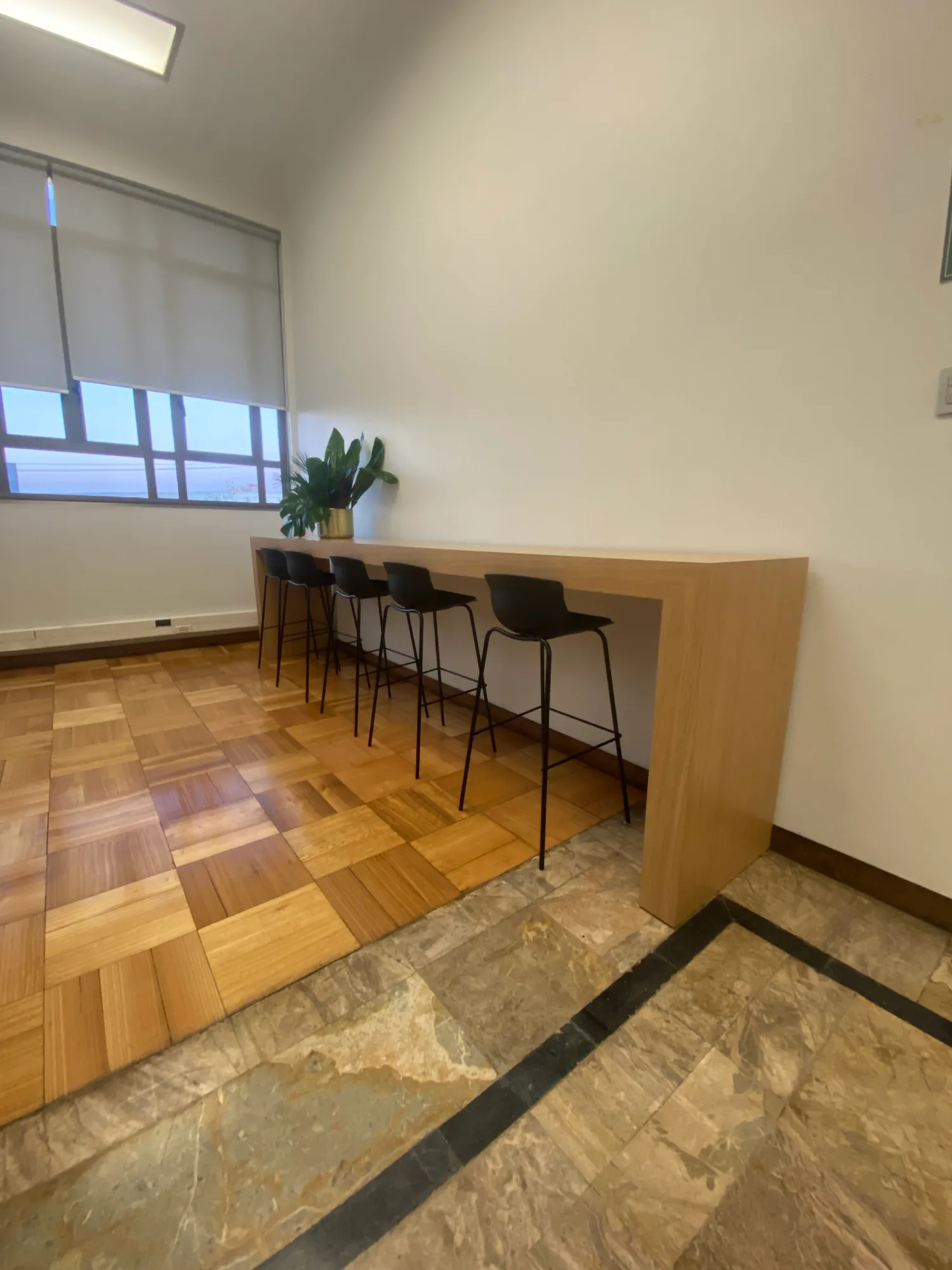 Barra alta de madera con taburetes negros.