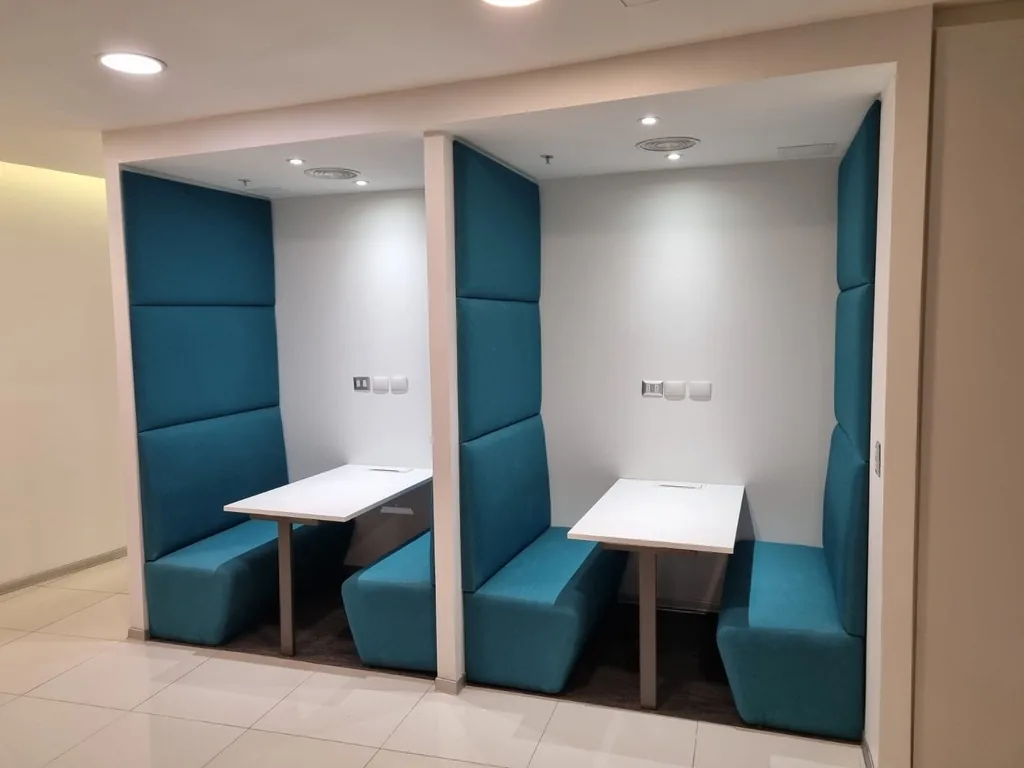 Cabinas de encuentro con mesas y tapizado azul.