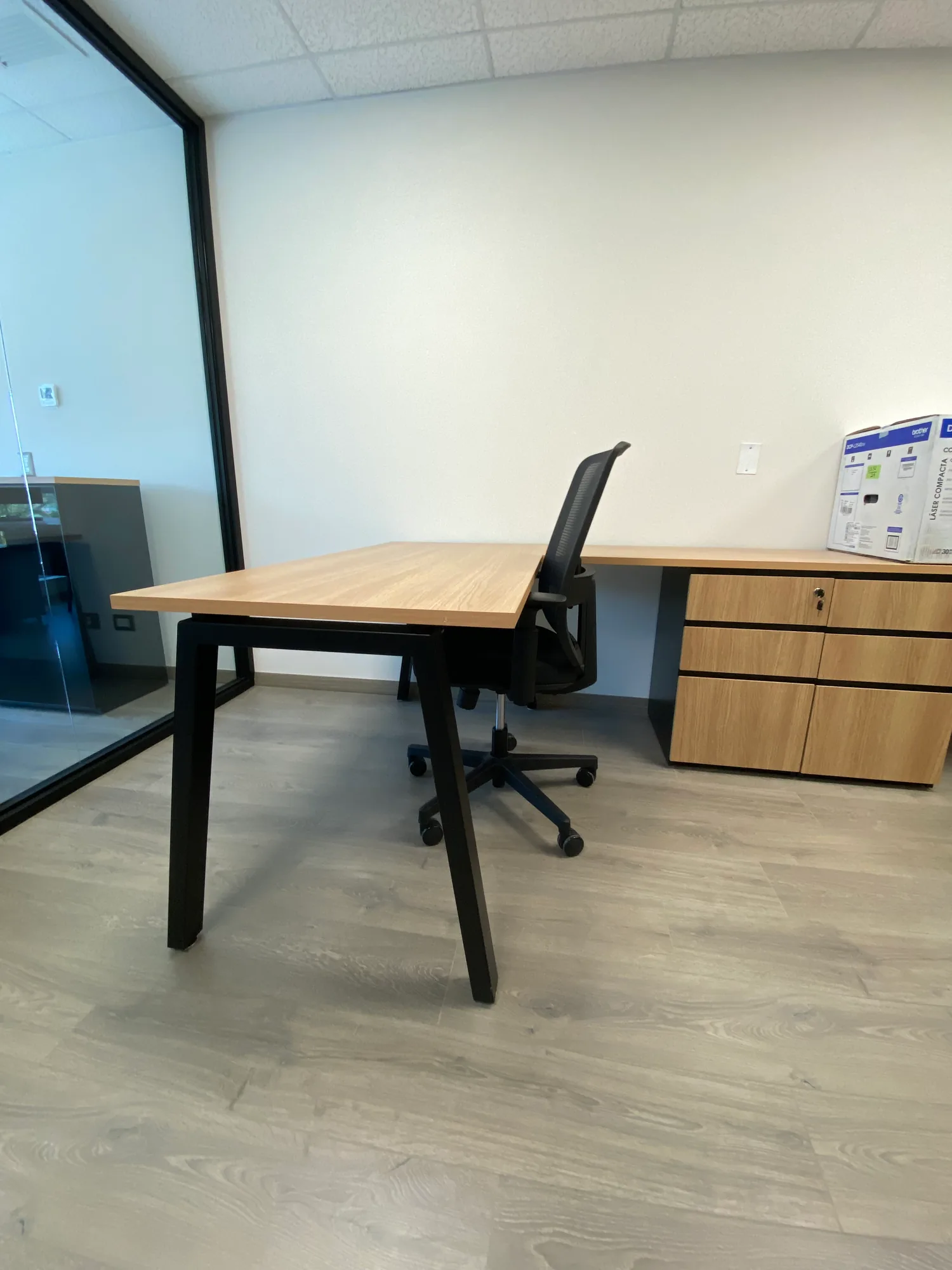 Escritorio con silla y cajonera en una oficina individual.