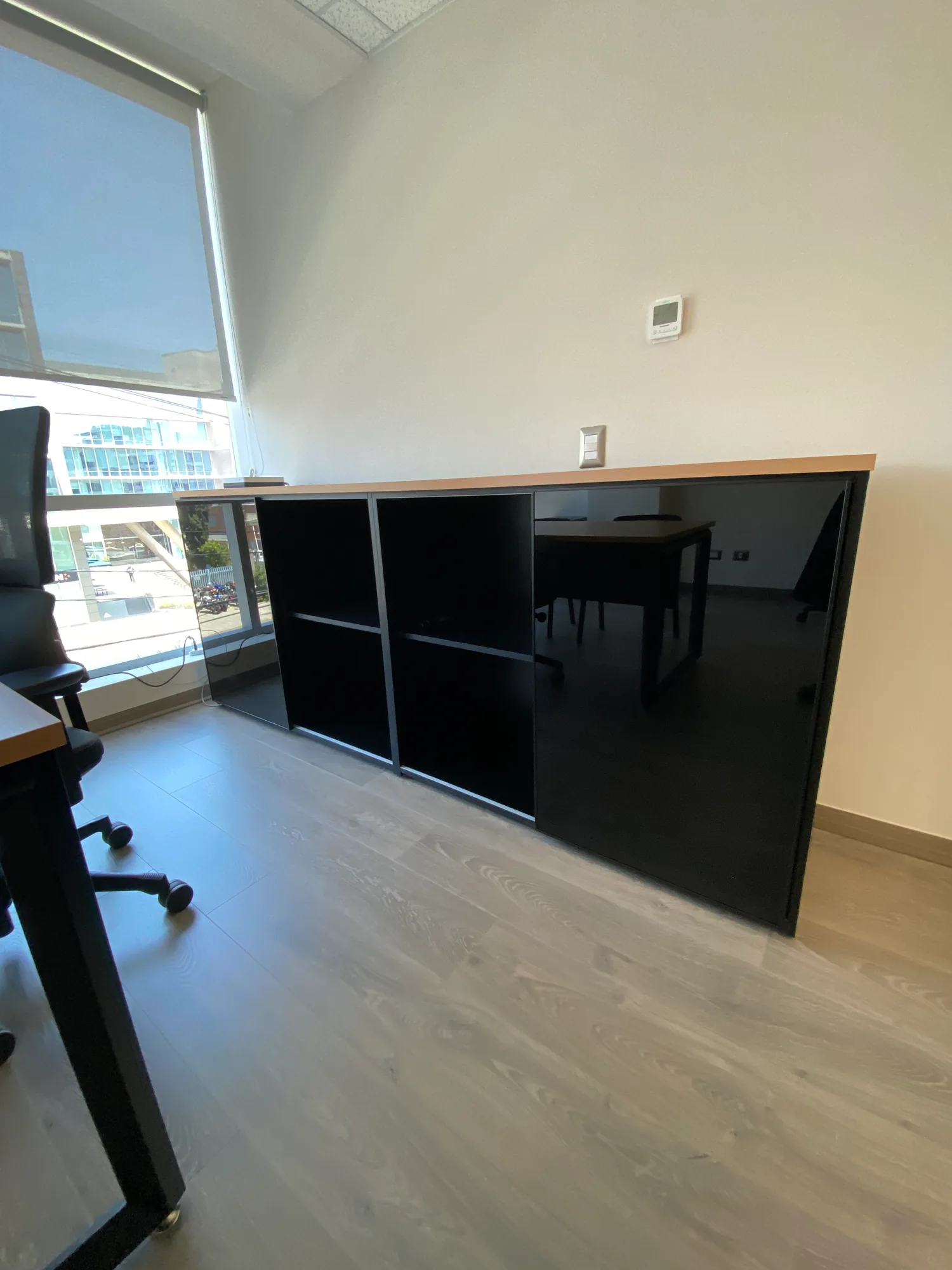 Mueble de guardado negro con cubierta de madera en una oficina.