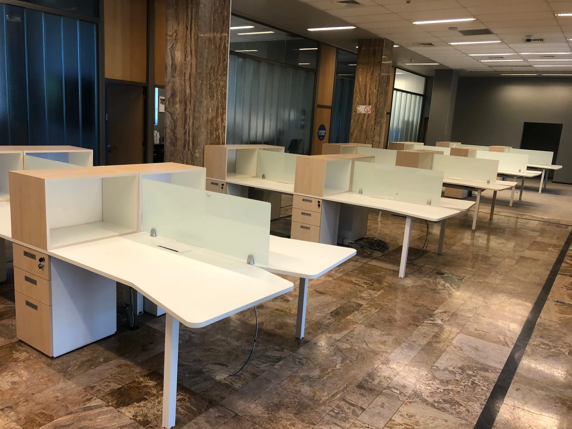 Conjunto de puestos de trabajo con divisores de vidrio.